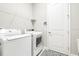 Bright laundry room with white washer and dryer, wire rack shelving, and decorative floor mat at 21807 Amelia Rose Way, Land O Lakes, FL 34637