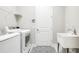 Bright laundry room with white washer and dryer, utility sink, and decorative floor mat at 21807 Amelia Rose Way, Land O Lakes, FL 34637