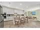 Modern kitchen featuring white cabinets, an island with seating, stainless steel appliances, and an adjacent dining area at 22990 Scaglione Dr, Lutz, FL 33549