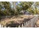 View of a fenced-in backyard featuring a shed with classic barn doors, set against a backdrop of mature trees at 9641 Fulton Ave, Hudson, FL 34667