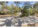 Long driveway leading to a cozy house, surrounded by lush trees and a shaded parking area at 9641 Fulton Ave, Hudson, FL 34667