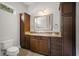 Bathroom with dark wood cabinets, granite counters, decorative mirror, and tile flooring at 11505 Heron Hills Ln, Riverview, FL 33569