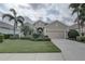 Charming single-story home with a two-car garage, lush landscaping, and mature palm trees on a cloudy day at 11610 Griffith Park Ter, Bradenton, FL 34211