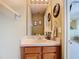 Bathroom features a single sink vanity with wooden cabinets, framed mirror, and nautical themed decor at 25950 Risen Star Dr, Wesley Chapel, FL 33544