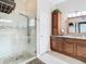 Bright bathroom featuring a glass shower, custom vanity with granite counters and a tall, matching cabinet at 25950 Risen Star Dr, Wesley Chapel, FL 33544