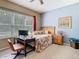 Bright bedroom features a computer desk, queen bed, and a large window with natural light at 25950 Risen Star Dr, Wesley Chapel, FL 33544