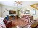 Comfortable living room with hardwood floors, a ceiling fan, and a large television set over a fireplace at 25950 Risen Star Dr, Wesley Chapel, FL 33544