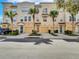 View of a three-story townhouse with a tan exterior, complemented by palm trees and individual garages at 3106 Bayshore Oaks Dr, Tampa, FL 33611