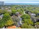 Aerial view of a residential neighborhood with mature trees, houses with diverse roof types, and Tampa Bay in the distance at 3115 W Fair Oaks Ave, Tampa, FL 33611