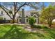 Lush green backyard featuring mature trees and a gray home with an outdoor brick patio at 3115 W Fair Oaks Ave, Tampa, FL 33611