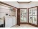 Bright laundry room featuring a washer, dryer, sink and shuttered windows with a view of the yard at 3115 W Fair Oaks Ave, Tampa, FL 33611