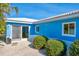 Turquoise back of the house with white gravel, bright blue walls, and well-maintained landscaping at 4550 Plaza Way, St Pete Beach, FL 33706