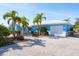 Charming blue single-story home featuring a white roof, palm trees, and a brick driveway at 4550 Plaza Way, St Pete Beach, FL 33706