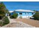 Charming light blue home with a white roof, complemented by gravel landscaping and lush greenery at 4550 Plaza Way, St Pete Beach, FL 33706