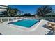 Sparkling community pool with ample seating, surrounded by a white fence and lush landscaping, perfect for relaxation and recreation at 4560 Overlook Ne Dr # 163, St Petersburg, FL 33703