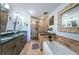 A luxurious bathroom featuring a double sink vanity, glass enclosed shower, and a soaking tub with decorative tile accents at 4937 Dover Ne St, St Petersburg, FL 33703