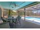 Covered patio featuring a ceiling fan, a table with seating, and view of the screened-in pool at 5357 Kirkwood Ave, Spring Hill, FL 34608