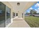 Covered patio with a white ceiling, concrete flooring, and access to a well-maintained backyard and side door at 6202 Belkton Ave, Spring Hill, FL 34608