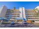 Exterior elevation of a multi-story condo building showcasing private balconies, lush landscaping, and covered parking at 7902 Sailboat Key S Blvd # 206, South Pasadena, FL 33707