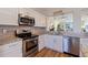 Close up of a kitchen featuring white cabinets, granite countertops, stainless steel appliances and wood flooring at 7902 Sailboat Key S Blvd # 206, South Pasadena, FL 33707