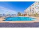 Outdoor pool surrounded by lounge chairs and umbrellas near the waterfront and complex at 7902 Sailboat Key S Blvd # 206, South Pasadena, FL 33707