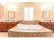 Elegant bathroom boasts dual vanities, a large soaking tub, and stylish lighting fixtures at 15944 Ternglade Dr, Lithia, FL 33547