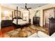 Comfortable bedroom with a four-poster bed, wood floors, plantation shutters and a ceiling fan at 15944 Ternglade Dr, Lithia, FL 33547