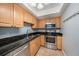 Modern kitchen featuring black granite counters, stainless steel appliances, and wooden cabinetry at 3711 W Iowa Ave # 214, Tampa, FL 33611
