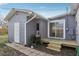 Exterior view of a home's gray siding, white door, wood deck and black grill against a blue sky at 4537 22Nd N St, St Petersburg, FL 33714