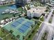 Aerial view of community tennis courts with boat docks, palm trees, and parking provides resort-style living at 7910 Sun Island S Dr # 305, South Pasadena, FL 33707