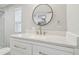 Stylish bathroom with a vanity, granite counters, modern finishes, and a decorative round mirror at 8408 Bob Wiggs Ave, Lithia, FL 33547