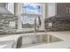 Close-up of a kitchen sink with stainless steel fixtures and tile backsplash under a bright window at 8408 Bob Wiggs Ave, Lithia, FL 33547