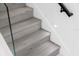 Modern staircase with wood-look steps, glass railing, LED step lighting, and a black handrail at 902 W Sligh Ave, Tampa, FL 33604