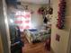 Small, cluttered bedroom with bed, wood floors, and window with a red and white striped curtain at 10539 Parkcrest Dr, Tampa, FL 33624