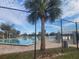 Community pool surrounded by lounge chairs visible through a black chain-link fence and palm trees at 10539 Parkcrest Dr, Tampa, FL 33624