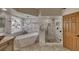 Bright bathroom featuring a soaking tub, glass shower, and vanity with unique vessel sink and natural stone tile at 1290 Clays Trl, Oldsmar, FL 34677