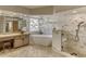 Bright bathroom featuring a soaking tub, glass shower, and vanity with unique vessel sink and natural stone tile at 1290 Clays Trl, Oldsmar, FL 34677
