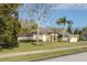 Attractive single-story home with mature trees, manicured lawn, and a three-car garage at 1405 Kensington Woods Dr, Lutz, FL 33549