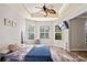 Comfortable main bedroom featuring tray ceilings, wood floors, and bright natural light through shuttered windows at 1405 Kensington Woods Dr, Lutz, FL 33549