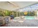 Spacious covered outdoor kitchen and dining area with pool and spa beyond at 1405 Kensington Woods Dr, Lutz, FL 33549