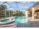 Inviting screened-in pool area with spa, brick pavers, and a cheerful yellow umbrella at 1405 Kensington Woods Dr, Lutz, FL 33549