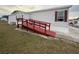 Ramped entrance of a single-story mobile home featuring red trim and neutral siding at 222 N Saint George Cir, Apollo Beach, FL 33572
