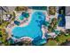 An aerial view of a large, uniquely shaped community pool surrounded by palm trees and lounge chairs at 410 Faraday Trl # A, Sun City Center, FL 33573