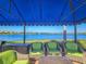 Covered outdoor seating area with plush wicker furniture and views of the lake and fountain at 5062 Stone Harbor Cir, Wimauma, FL 33598