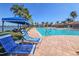 Lounge seating on the pool deck overlooking a lake with a fountain and shady umbrellas at 5062 Stone Harbor Cir, Wimauma, FL 33598