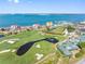 Aerial of golf course highlighting water features and landscaping with waterfront condos, marina, and ocean backdrop at 6177 Sun Blvd # 401, St Petersburg, FL 33715