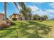 Expansive backyard featuring mature palms, lake view, and screened in lanai at 5062 Stone Harbor Cir, Wimauma, FL 33598