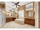 This bathroom features a tub, glass shower, double vanities, decorative wallpaper, and a ceiling fan at 5062 Stone Harbor Cir, Wimauma, FL 33598