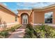 Elegant home entrance featuring an arched entryway, brick path, double doors, and manicured landscaping at 5062 Stone Harbor Cir, Wimauma, FL 33598