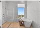 Bright bathroom featuring a soaking tub by a large window and a glass-enclosed shower with marble tile at 1020 Sunset Point Rd # 703, Clearwater, FL 33755